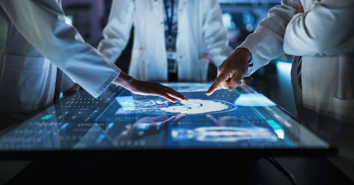 Hospital Medical Research Center: Focus On Hand Gestures Of Diverse Colleagues Gathered Around Interactive Touch Screen Table With MRI Scans Of Brain On Display.